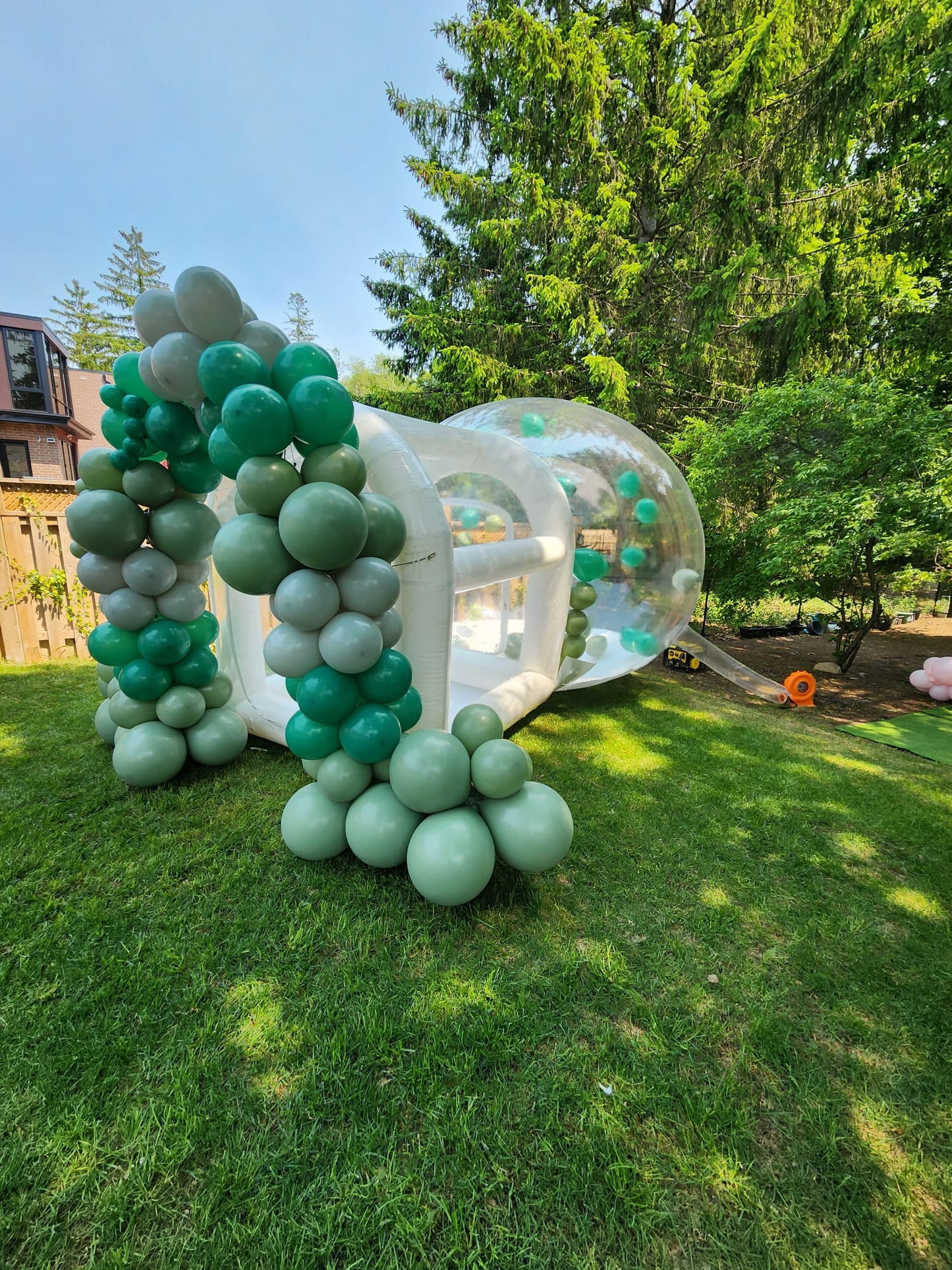 Transparent bubble house from Aura Luxury Rental Ltd, showcasing its round shape and clear inflatable walls in a scenic outdoor setting.