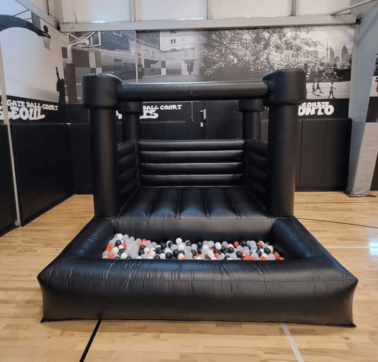 Black bouncy castle with attached ballpit from Aura Luxury Rental Ltd, featuring colorful balls and a spacious jumping area.