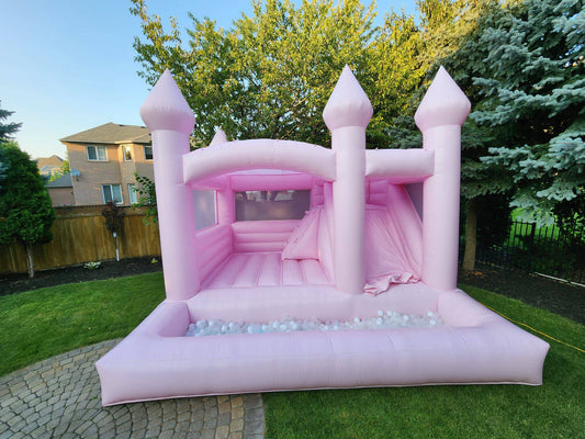 Pink princess castle bounce house with colorful ball pit for kids, featuring towers and castle details, by Aura Luxury Rental Ltd.
