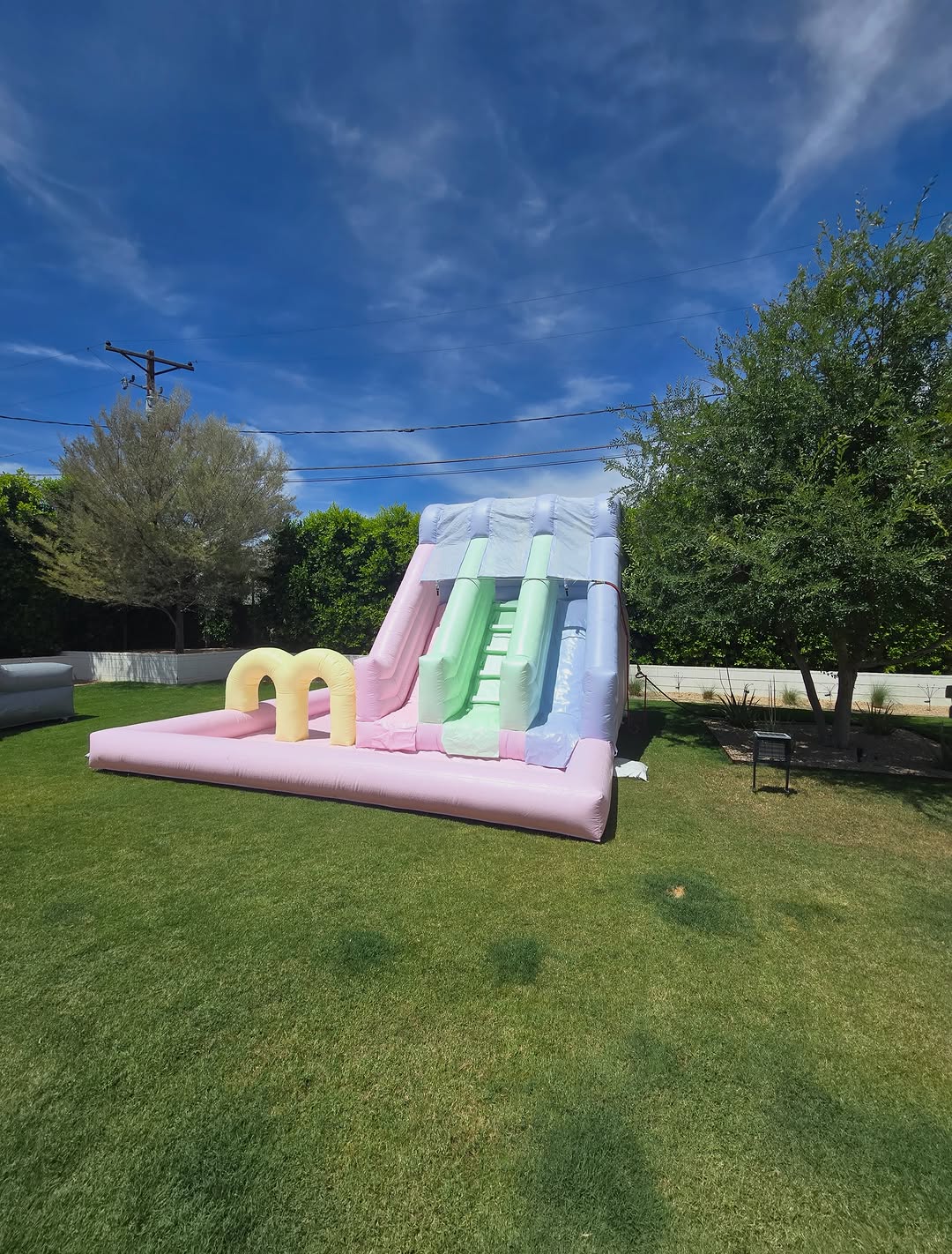 Colorful rainbow waterslide by Aura Luxury Rental Ltd, featuring vibrant slides and playful water features in an outdoor setting.
