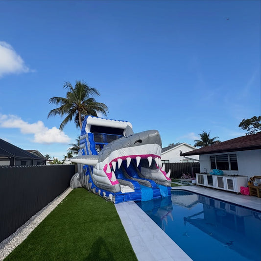 Giant shark water slide by Aura Luxury Rental Ltd featuring a large, colorful inflatable shark design for outdoor fun.