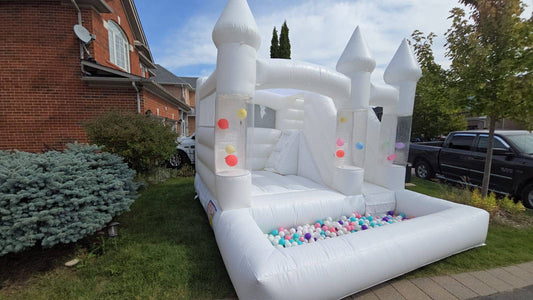 White balloon pillar castle with slide and ballpit for kids, designed by Aura Luxury Rental Ltd, featuring colorful play elements.