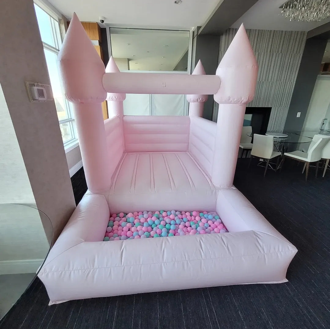 Baby pink bounce house with an attached ballpit from Aura Luxury Rental Ltd, featuring colorful inflatable play area for children.